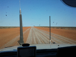 Driving along a straight red dirt road