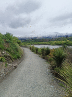 Trail running along a river with mountains in the background