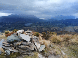 Rock cairn looking south with Lake Hayes, Remarkables and Lake Whakatipu in the distance with scattered showers